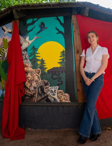 Artist standing beside their artwork