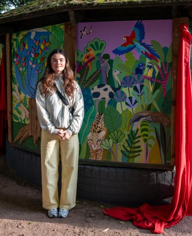 artist standing beside their artwork 