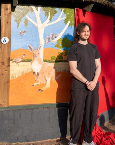Artist standing by their work 